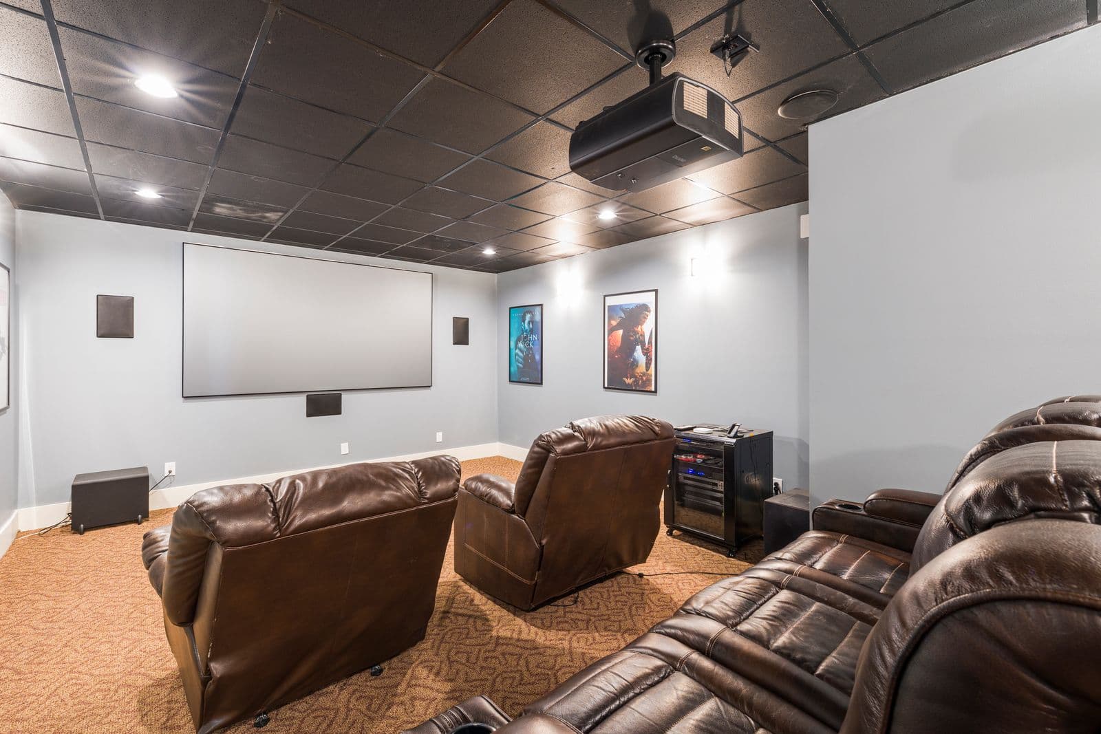 Home cinema room with plush leather armchairs arranged to face the screen wall